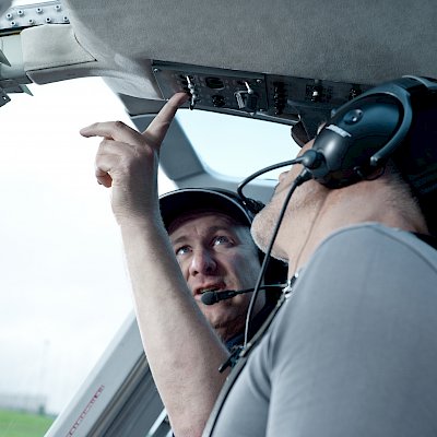 Ein Mann erklärt einem anderen Mann Instrumente im Hubschrauber